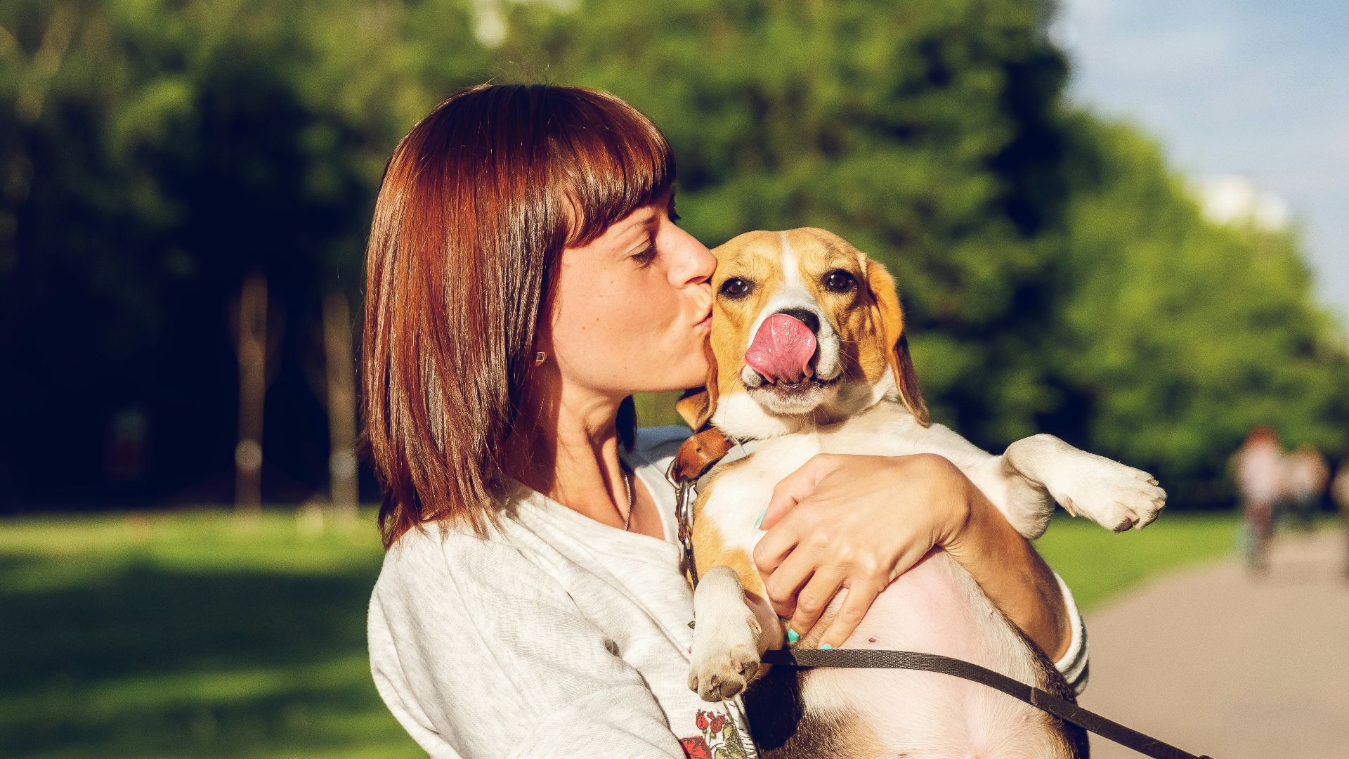 woman carrying and kissing dog