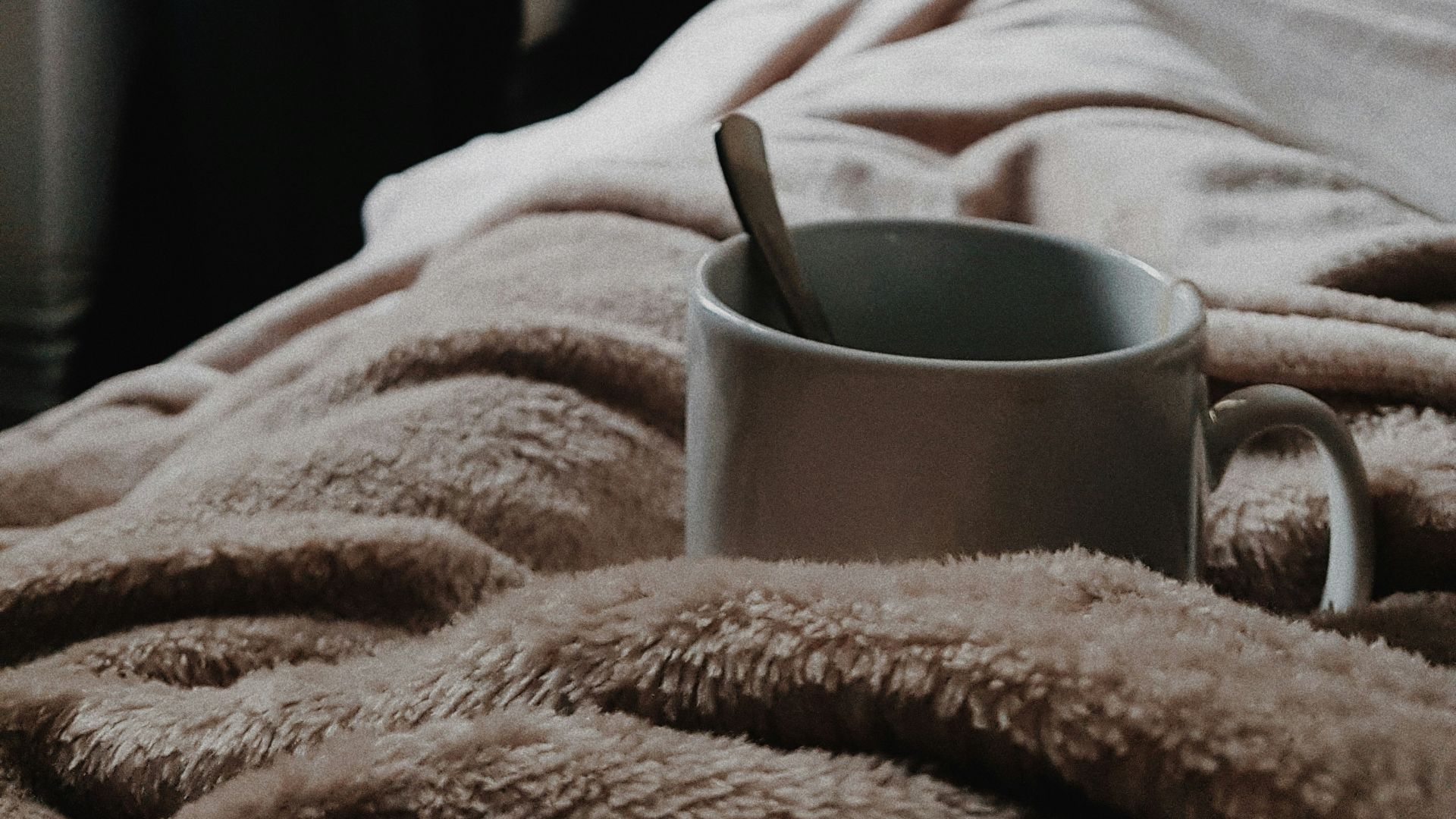 white ceramic mug on bed