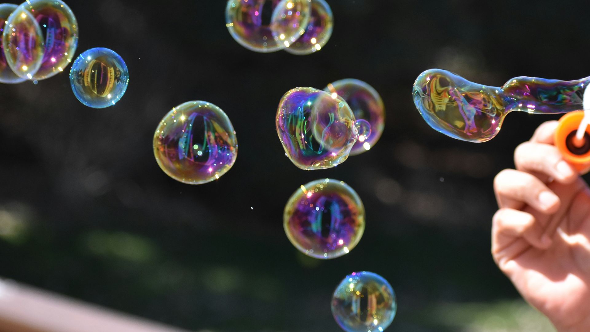 a person holding a pair of scissors in front of soap bubbles