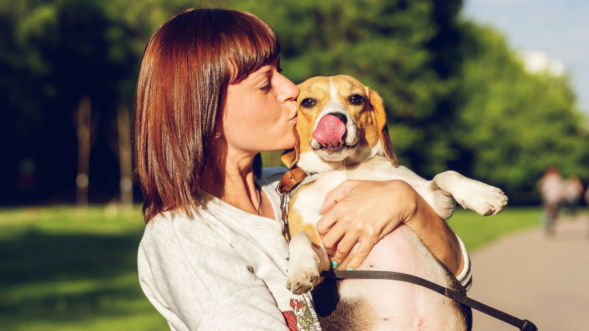 woman carrying and kissing dog
