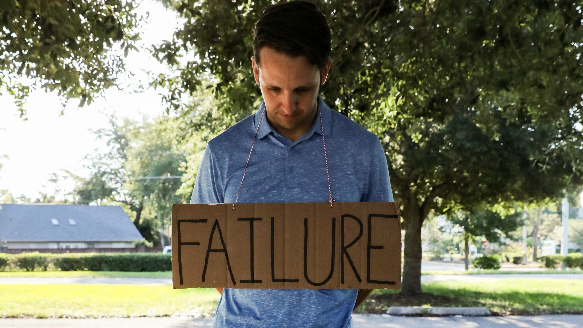 man in blue and white crew neck t-shirt holding brown wooden signage