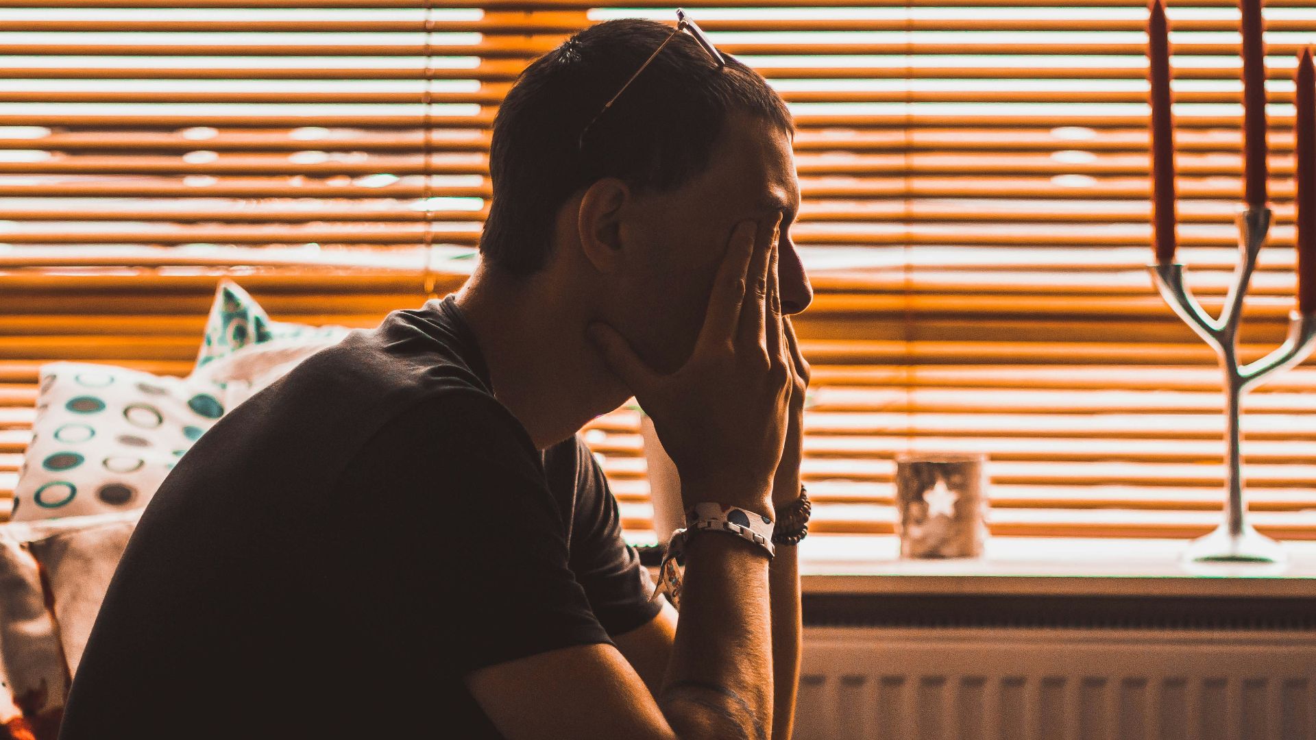 man sitting on chair covering his eyes