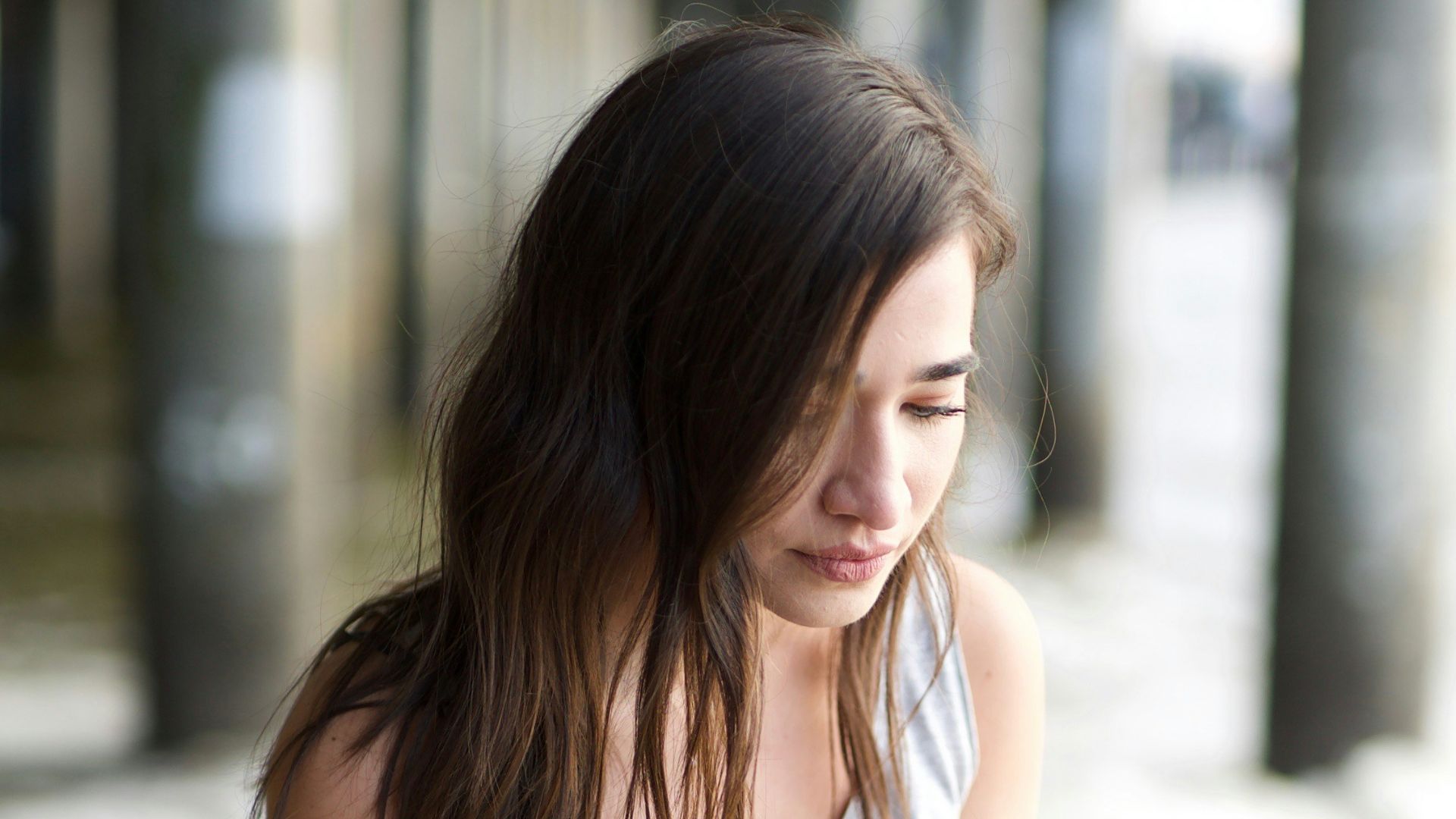woman in white tank top and blue denim jeans sitting on concrete floor during daytime