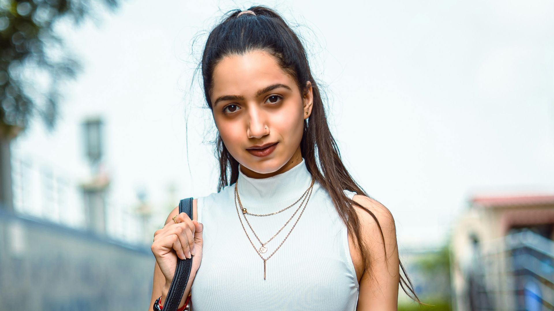 woman in white tank top and red shorts holding black leather handbag