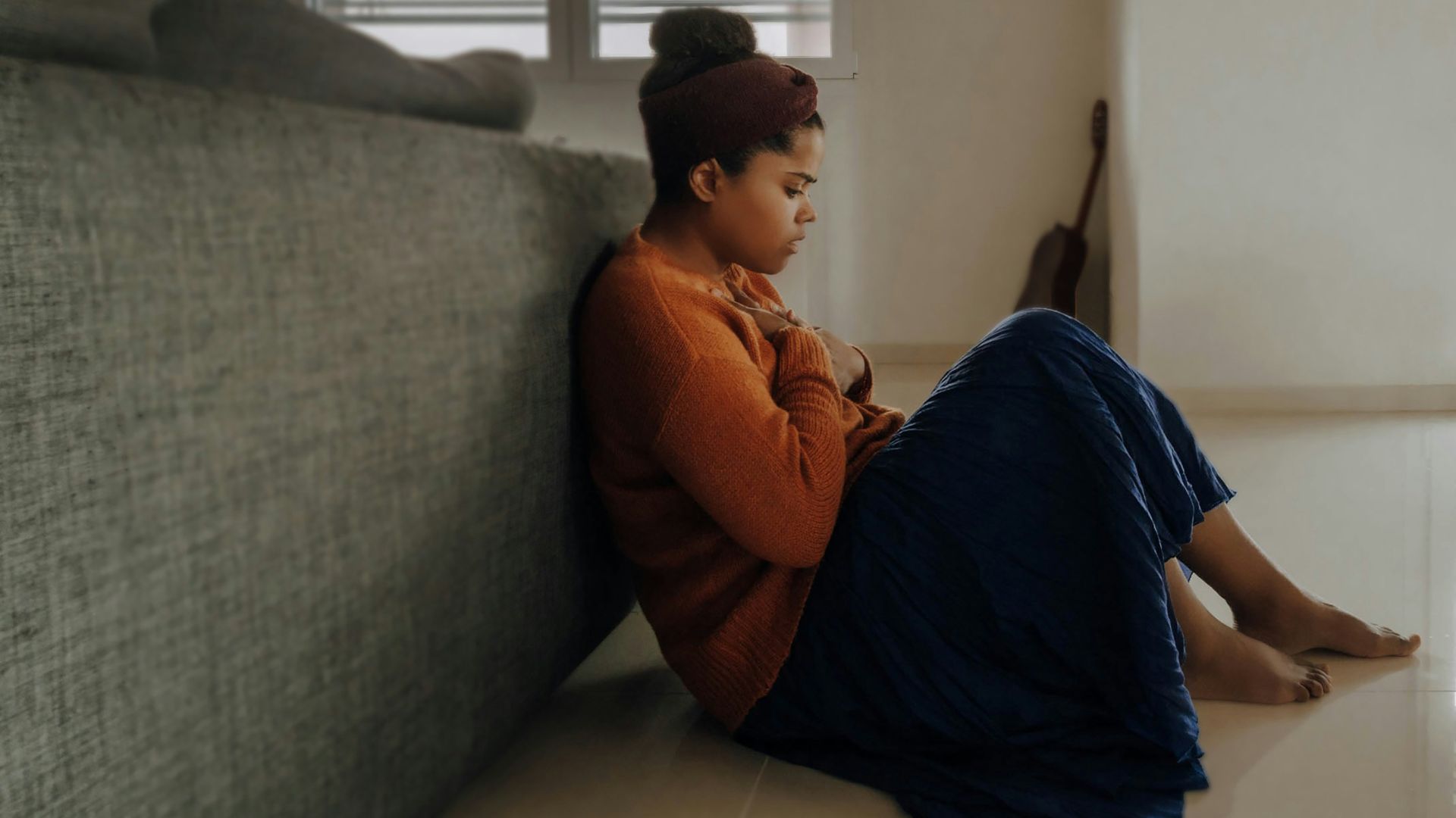 man in orange long sleeve shirt sitting on gray couch