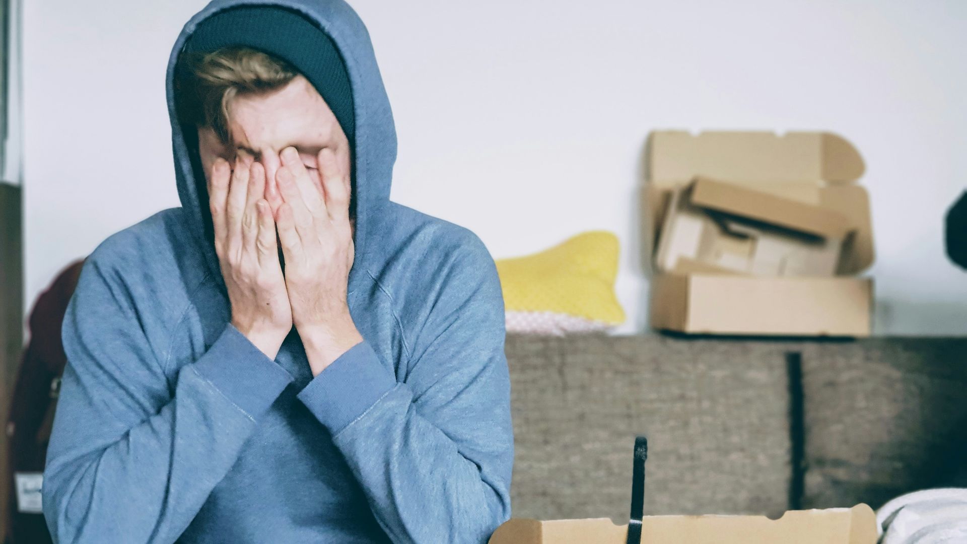 man covering face with both hands while sitting on bench