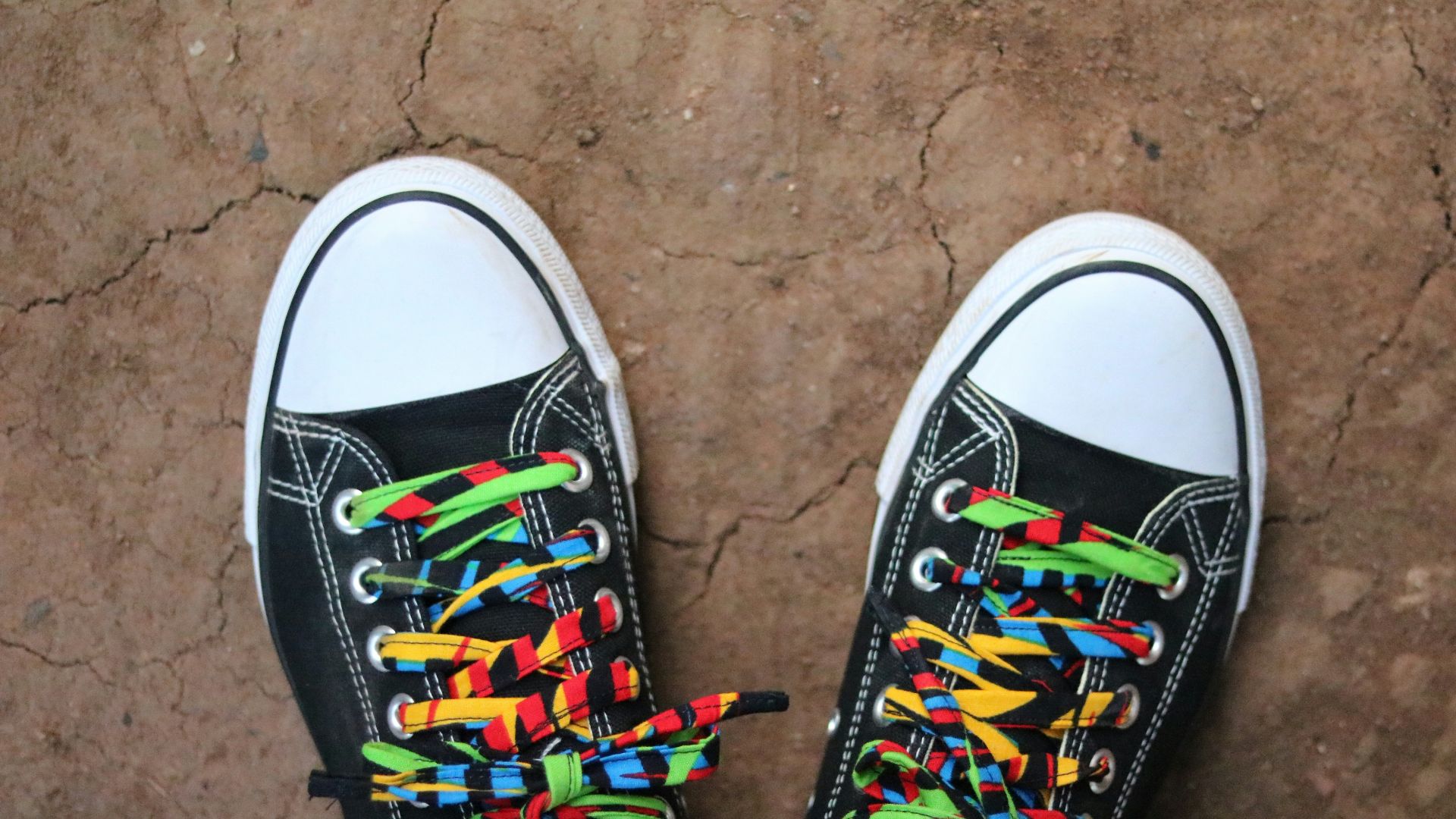 a pair of black shoes with colorful laces on them