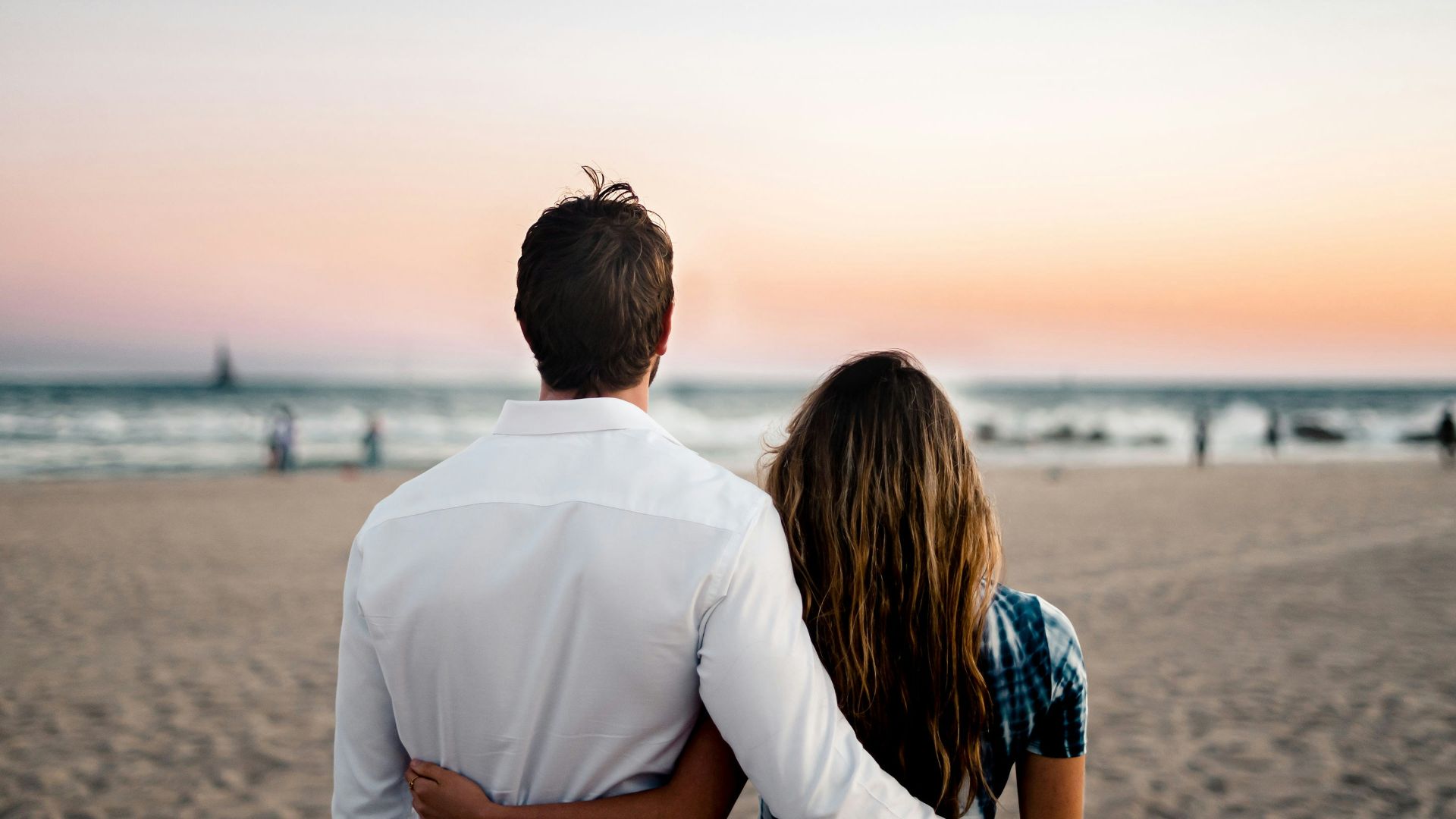man and woman standing on brown sand during daytime