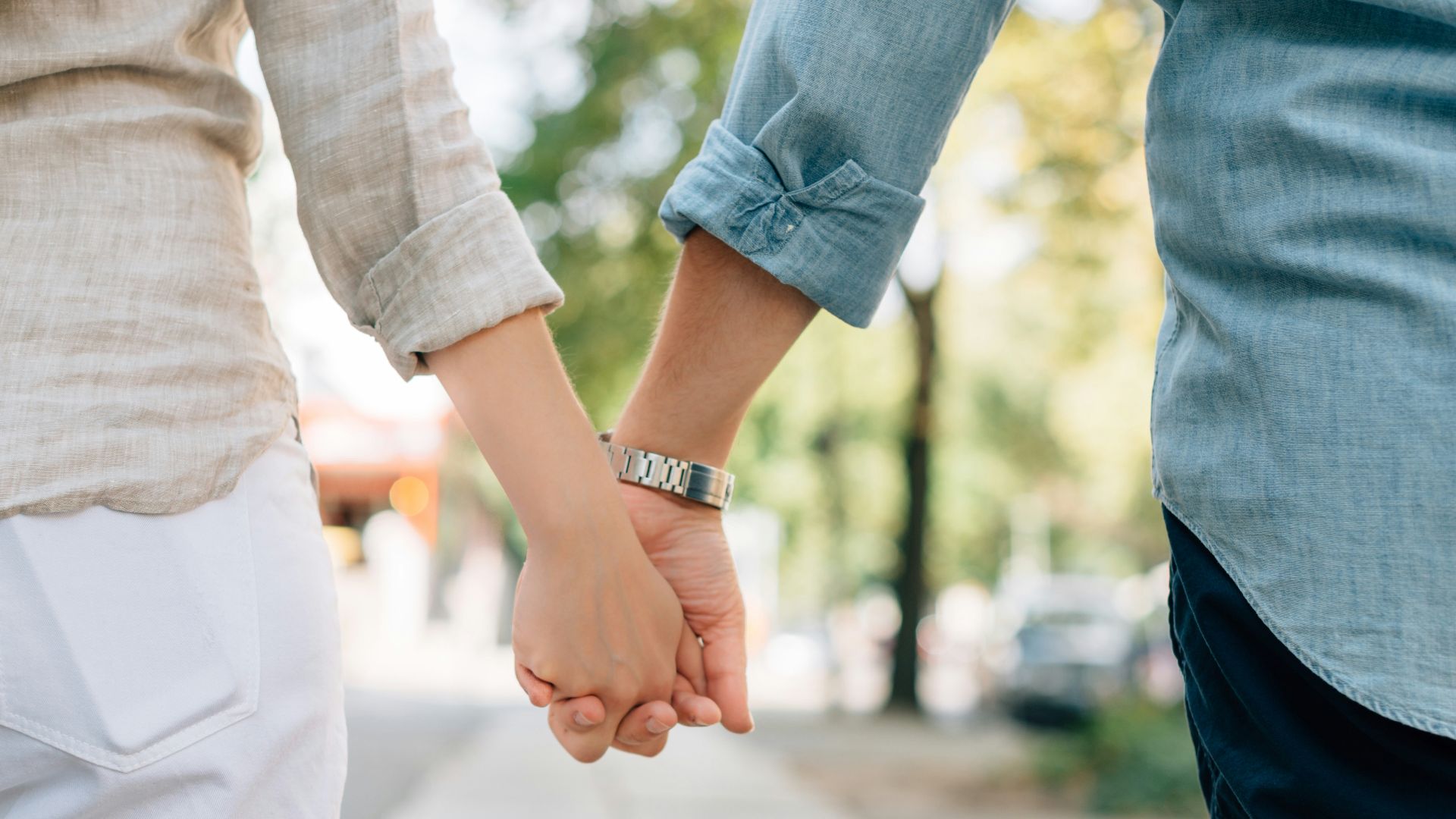 man and woman holding hands together in walkway during daytime