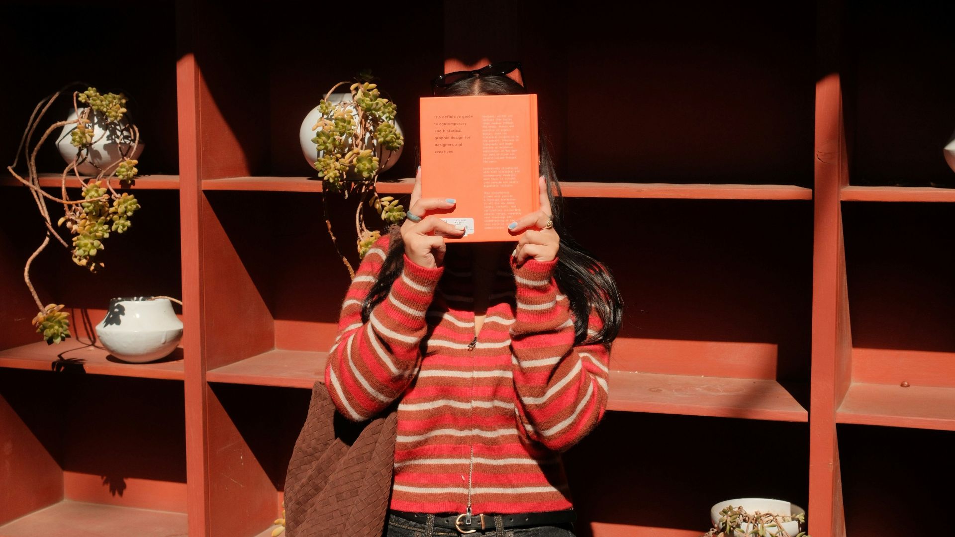 Person holds orange book in front of face
