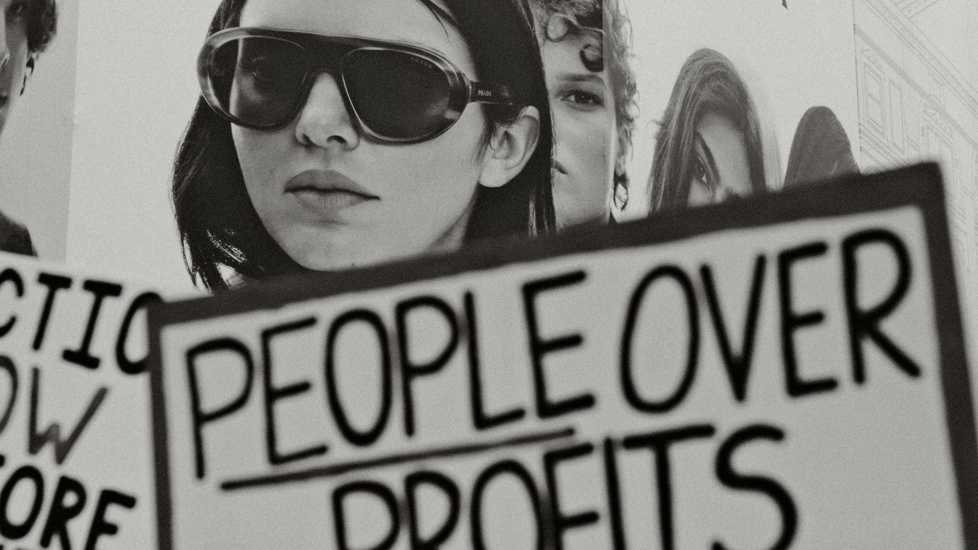 Woman holding sign people over profits