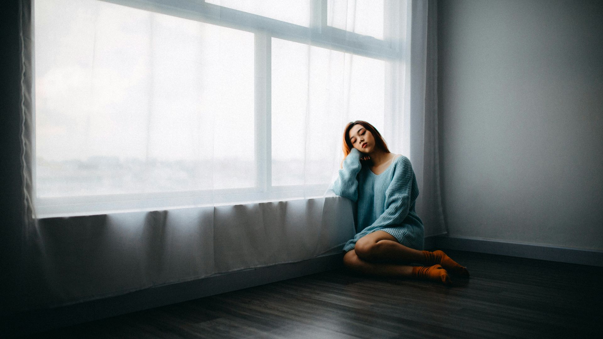 woman sitting on floor near window