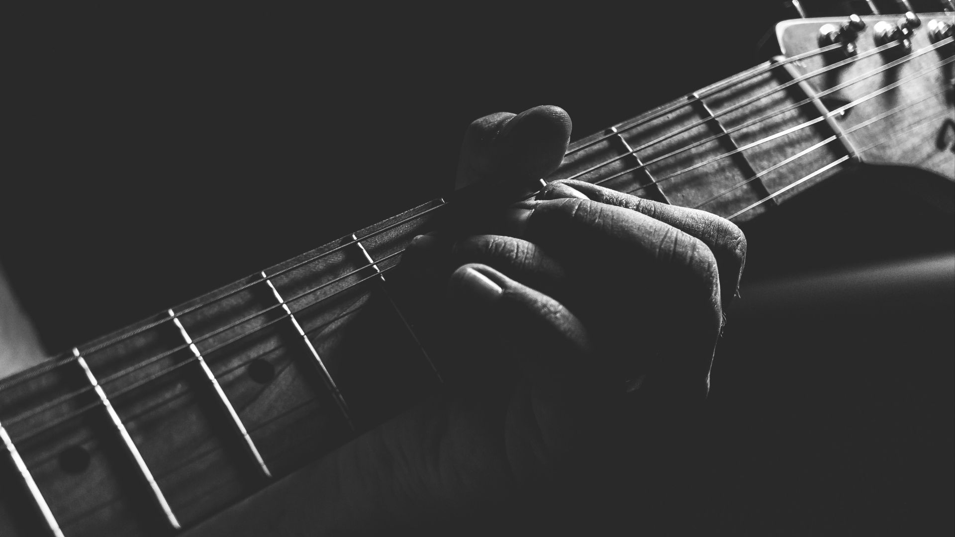 grayscale photo of person holding guitar neck and strings