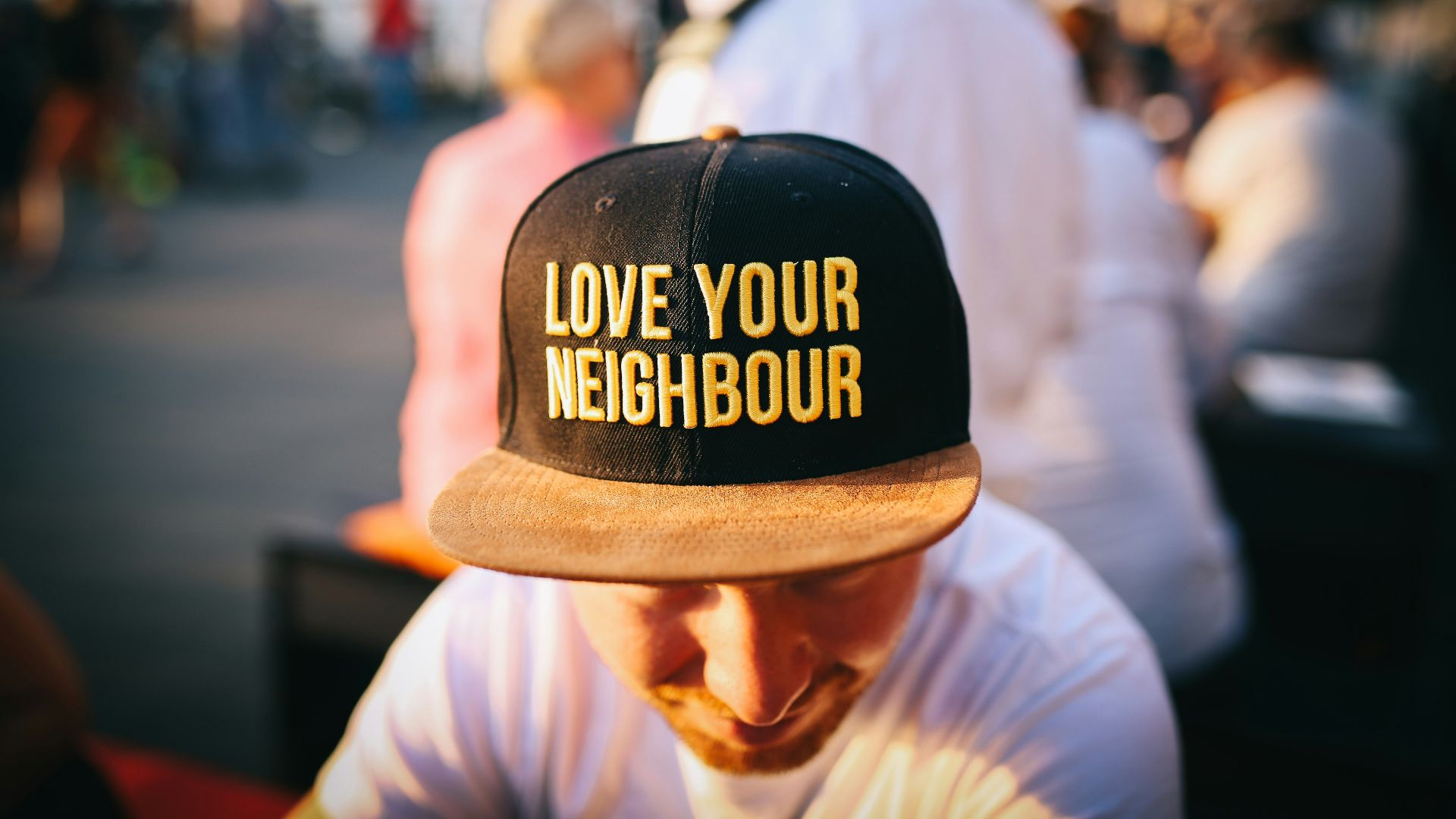 man wearing black cap with love your neighbour print during daytime