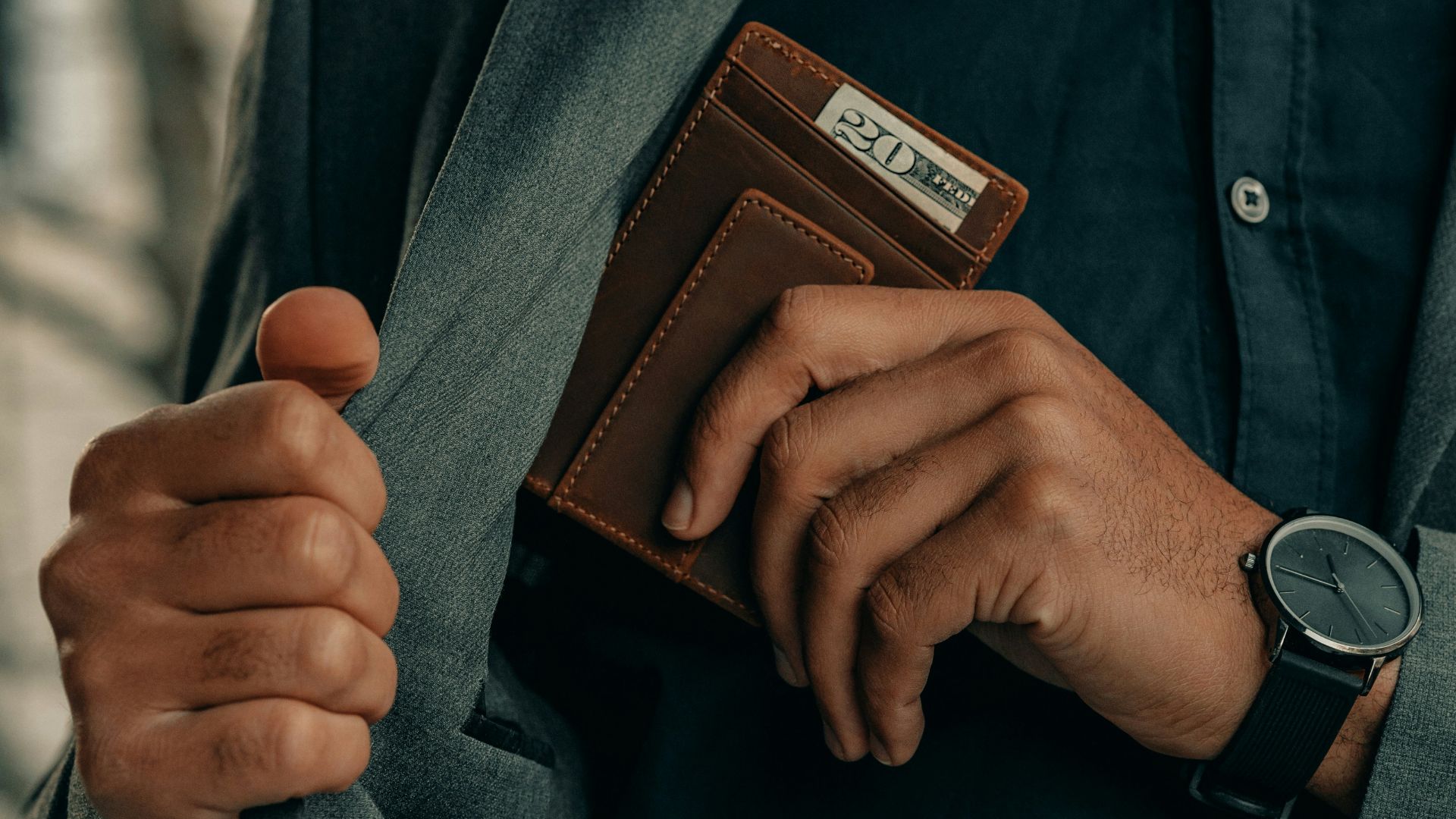 a man holding a wallet and a watch
