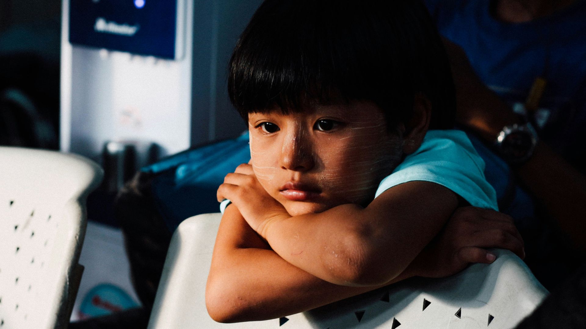 boy leaning on white chair