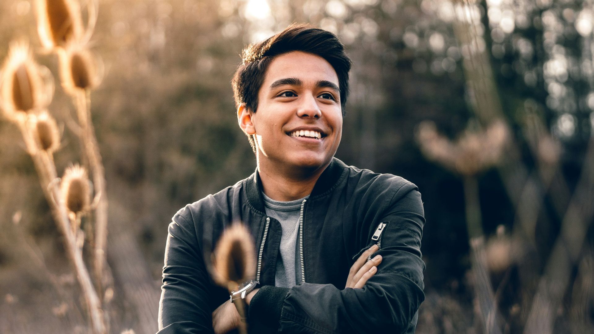 smiling man standing near green trees