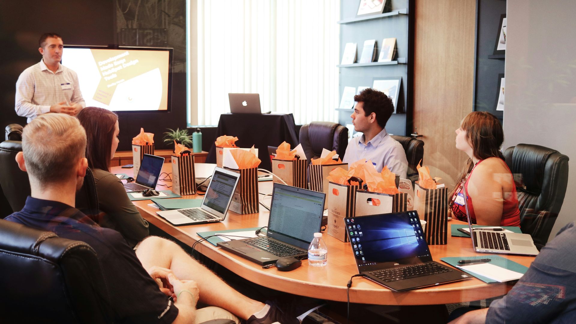 man standing in front of people sitting beside table with laptop computers