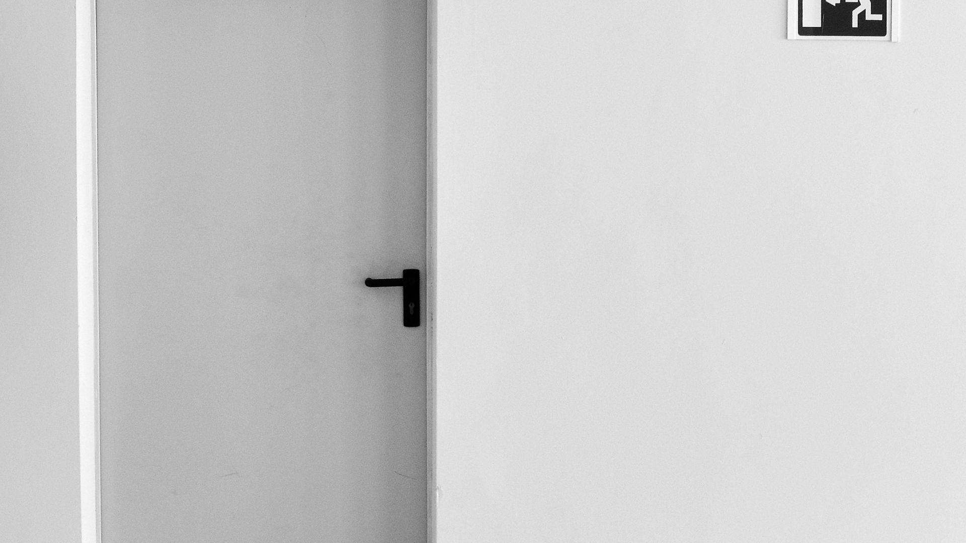 closed white painted door with exit signage
