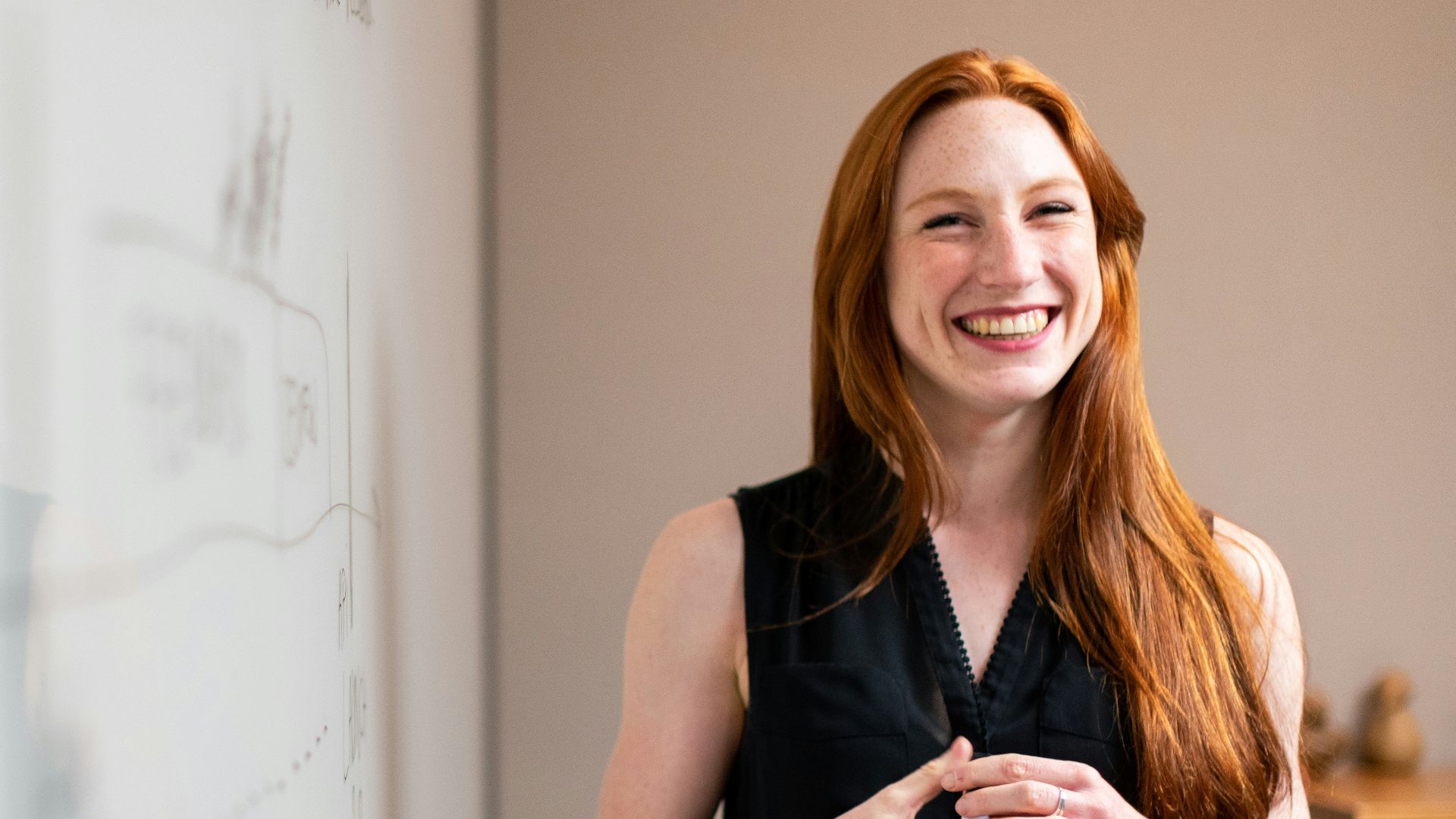 woman in blue tank top standing beside white wall