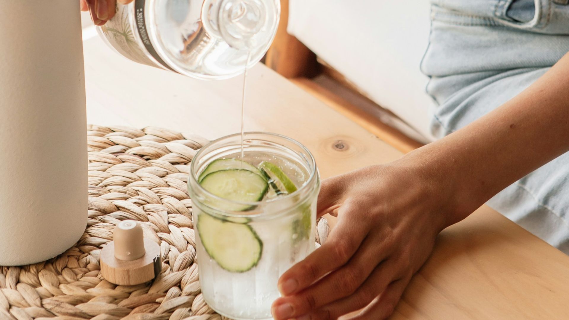 woman in white tank top pouring water on clear drinking glass