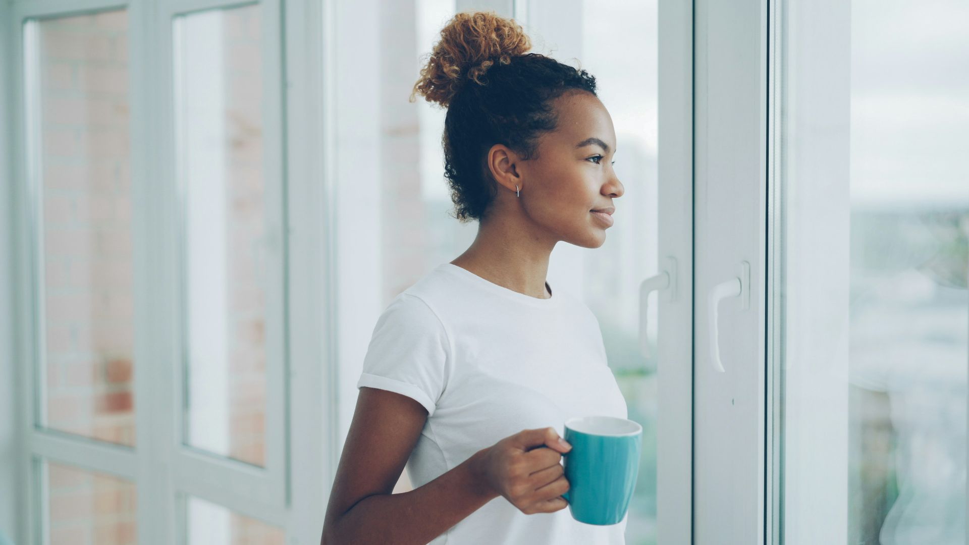 Woman holding mug looking out window