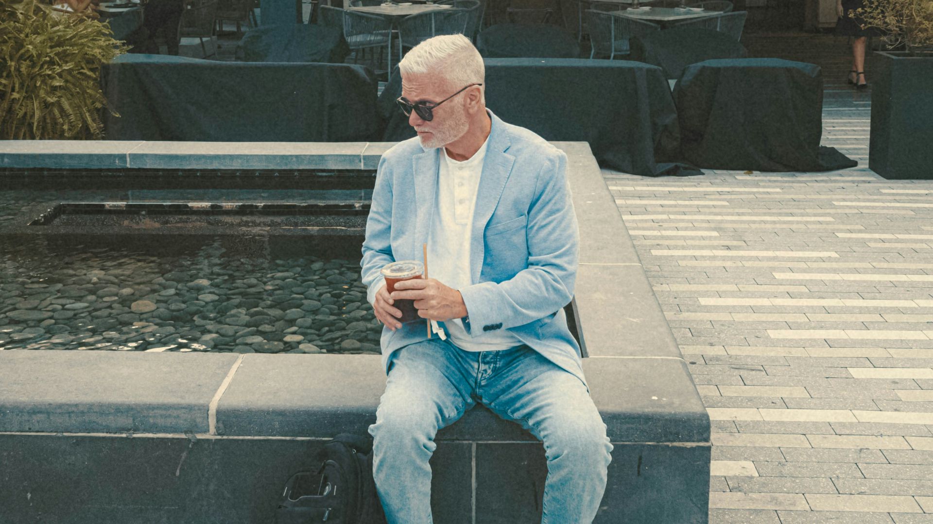 a man sitting on a bench next to a fountain