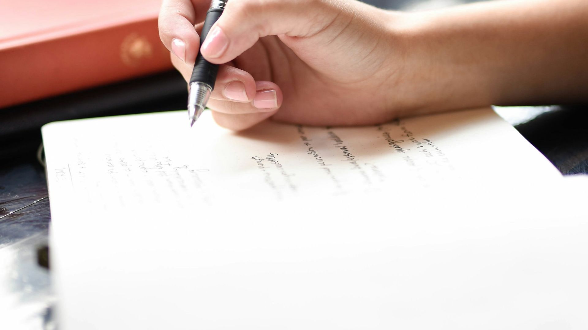 a person writing on a piece of paper with a pen