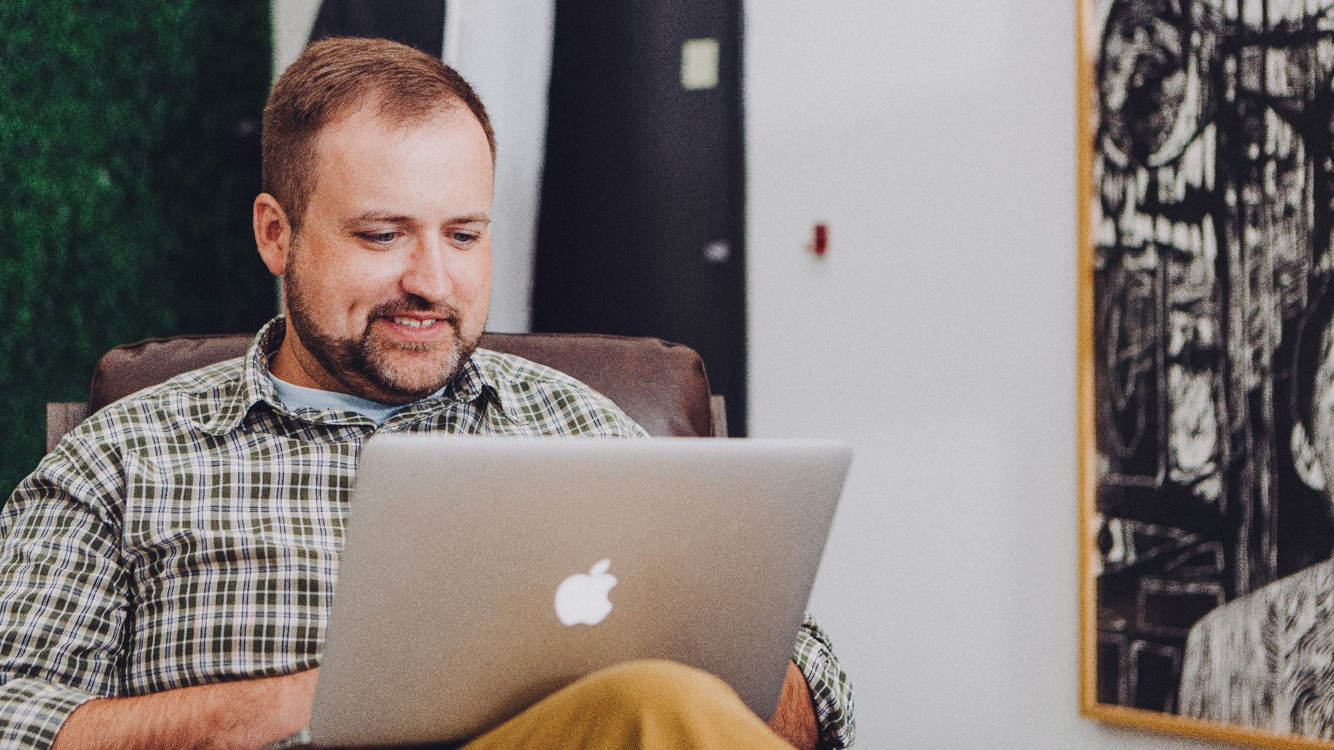 man smiling and using MacBook