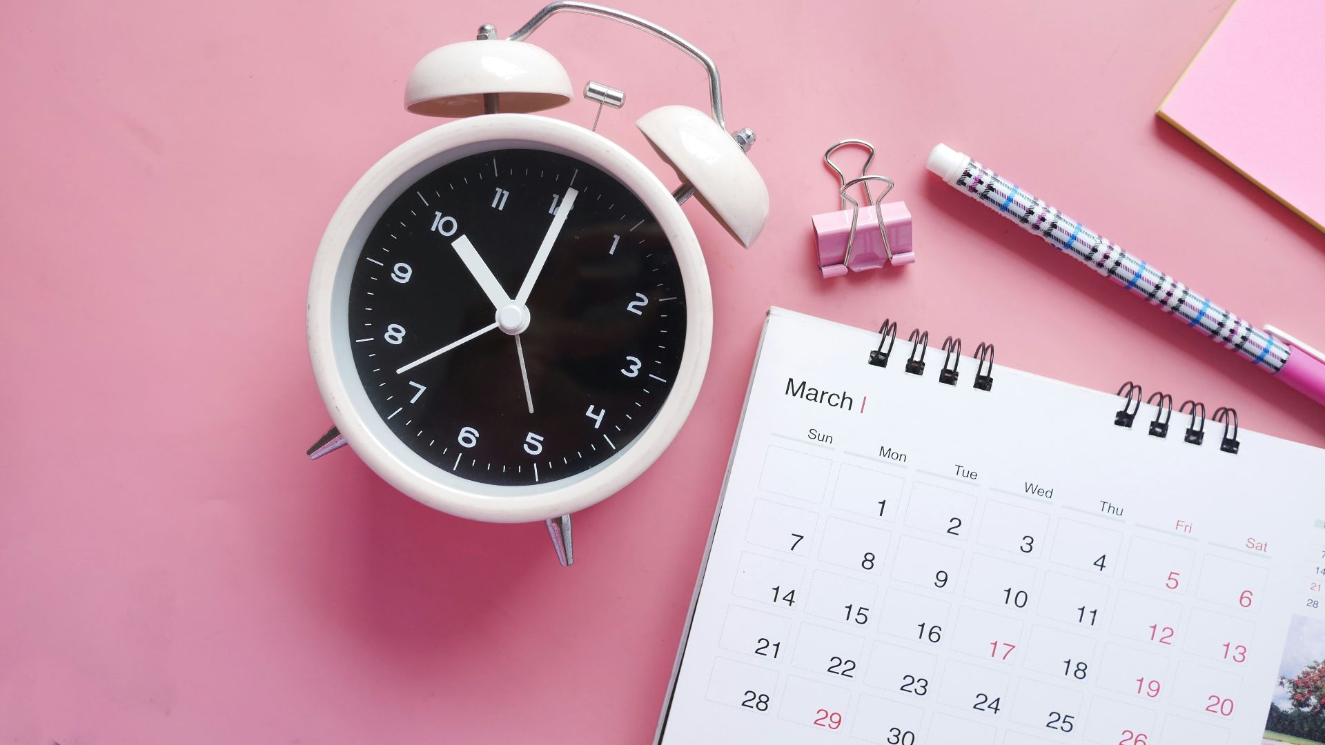white and pink analog alarm clock