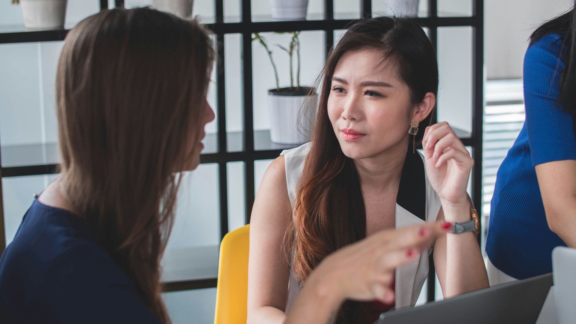 woman sitting on yellow armless chair near gray laptop computer