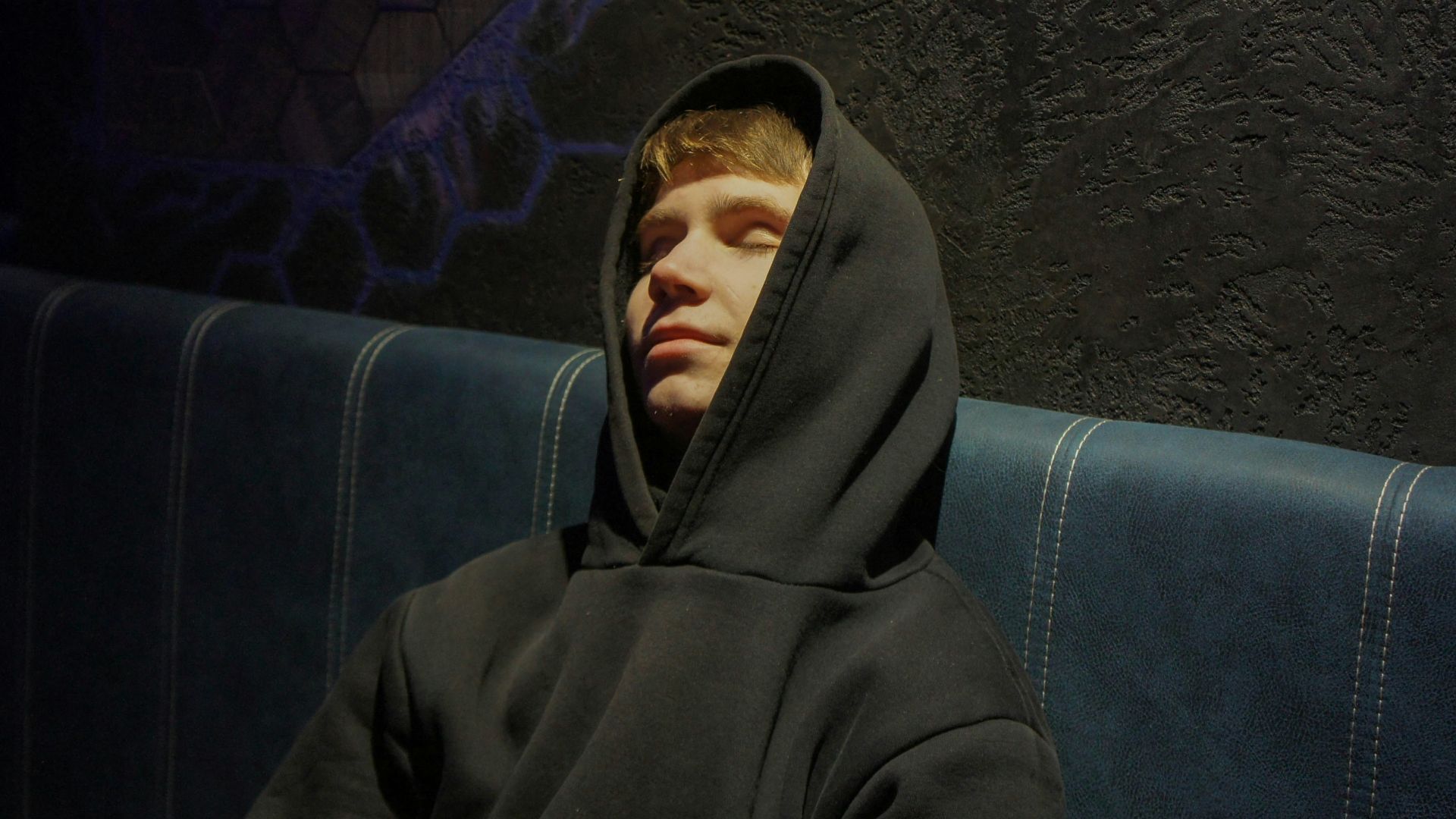 a man in a hoodie sitting on a bench