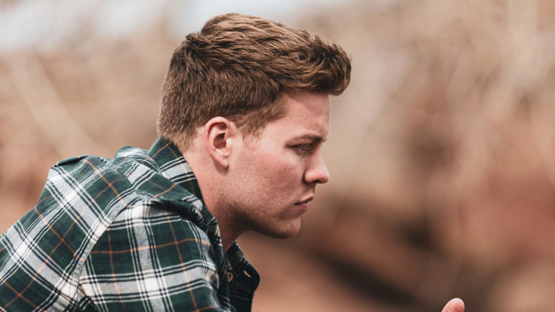 man in black white and gray plaid dress shirt holding smartphone