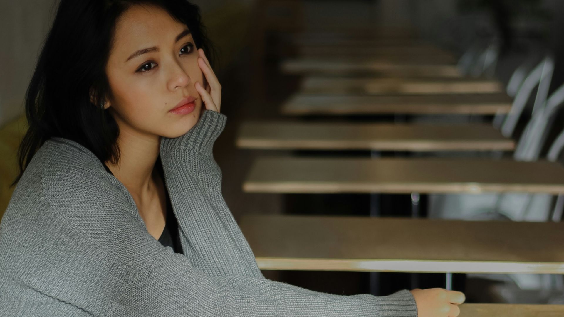 Young woman sitting at empty cafe tables