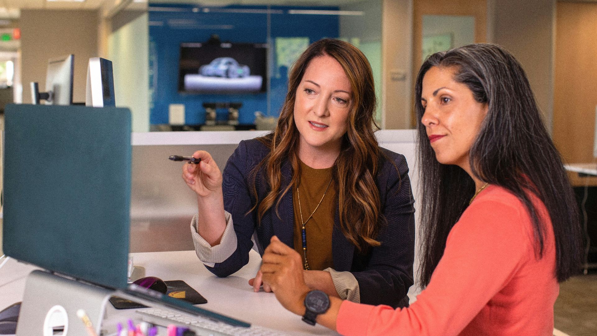 two women sitting at a table looking at a computer screen