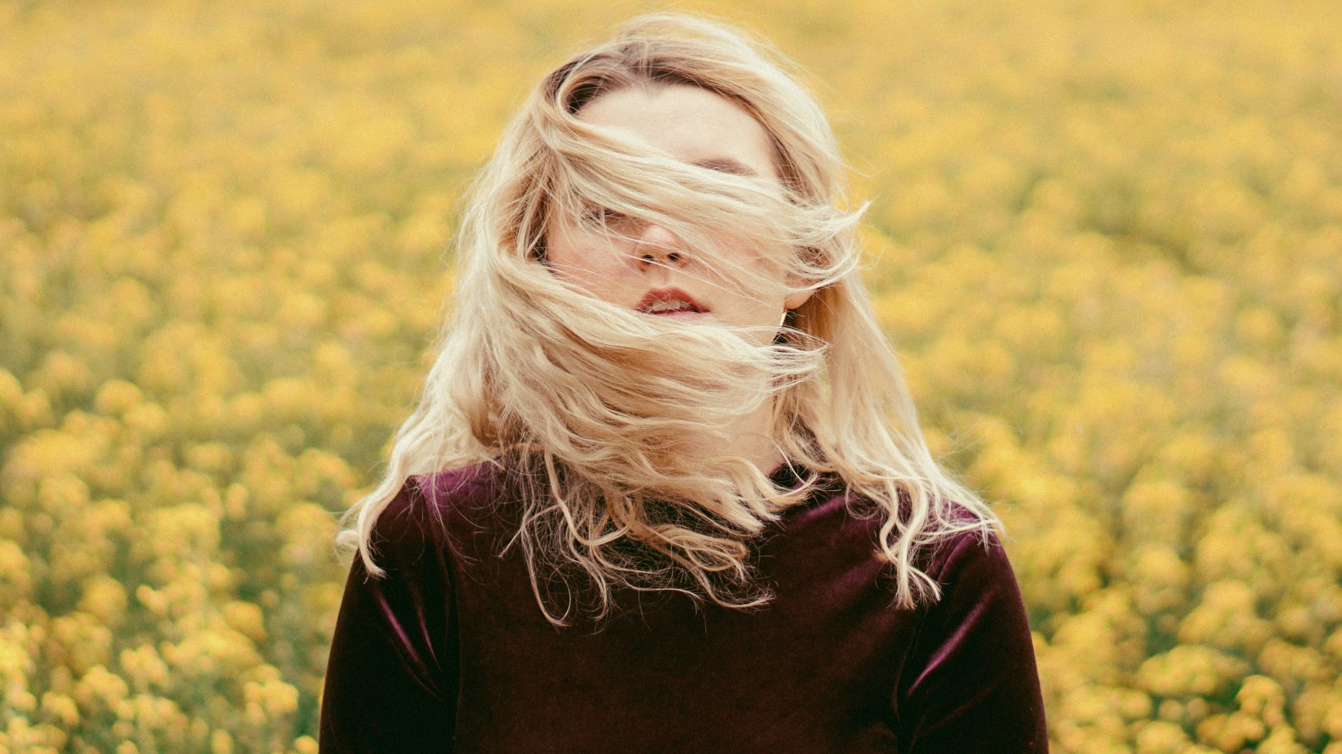 woman in black long sleeve shirt standing on yellow flower field during daytime