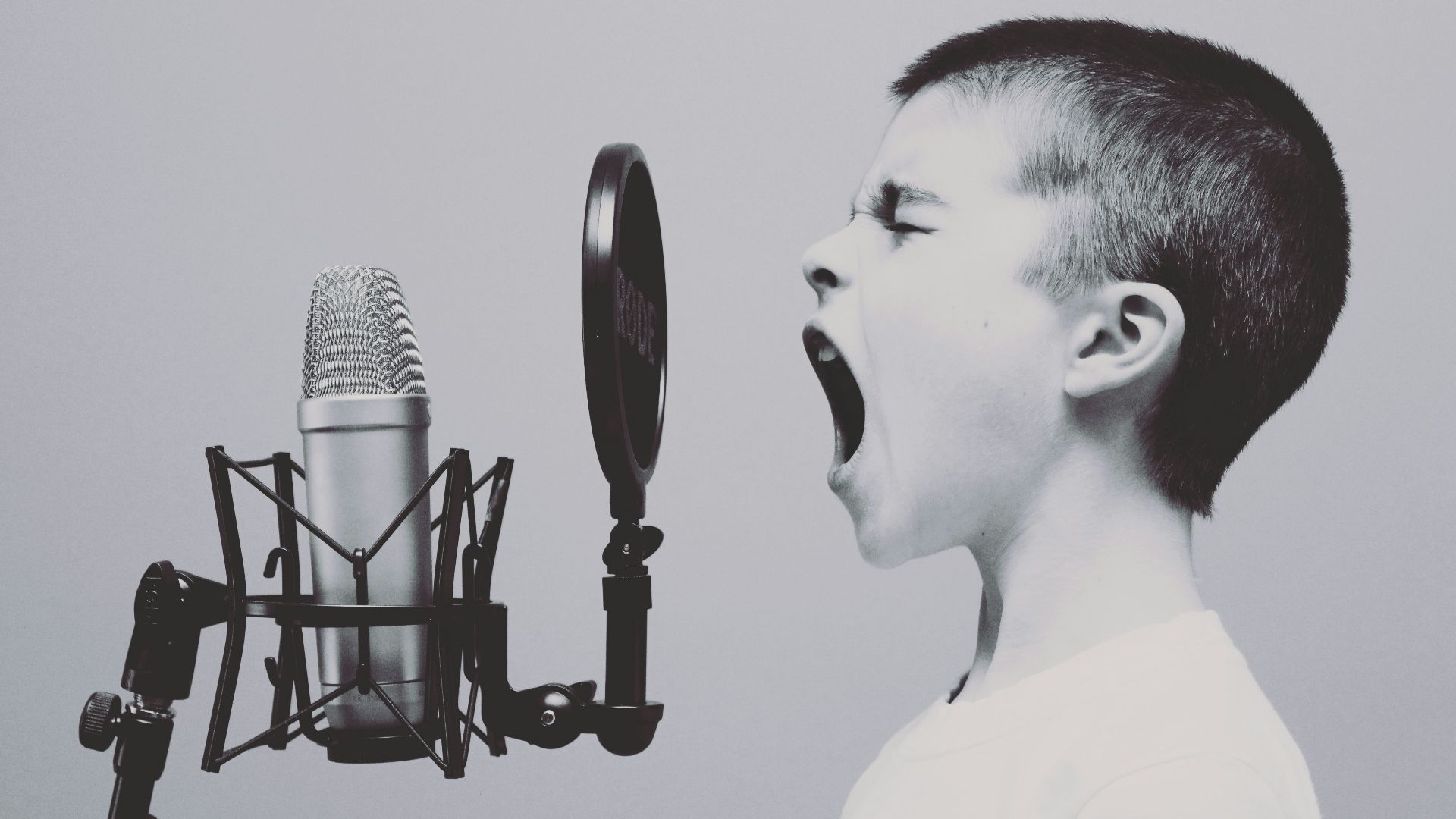 boy singing on microphone with pop filter