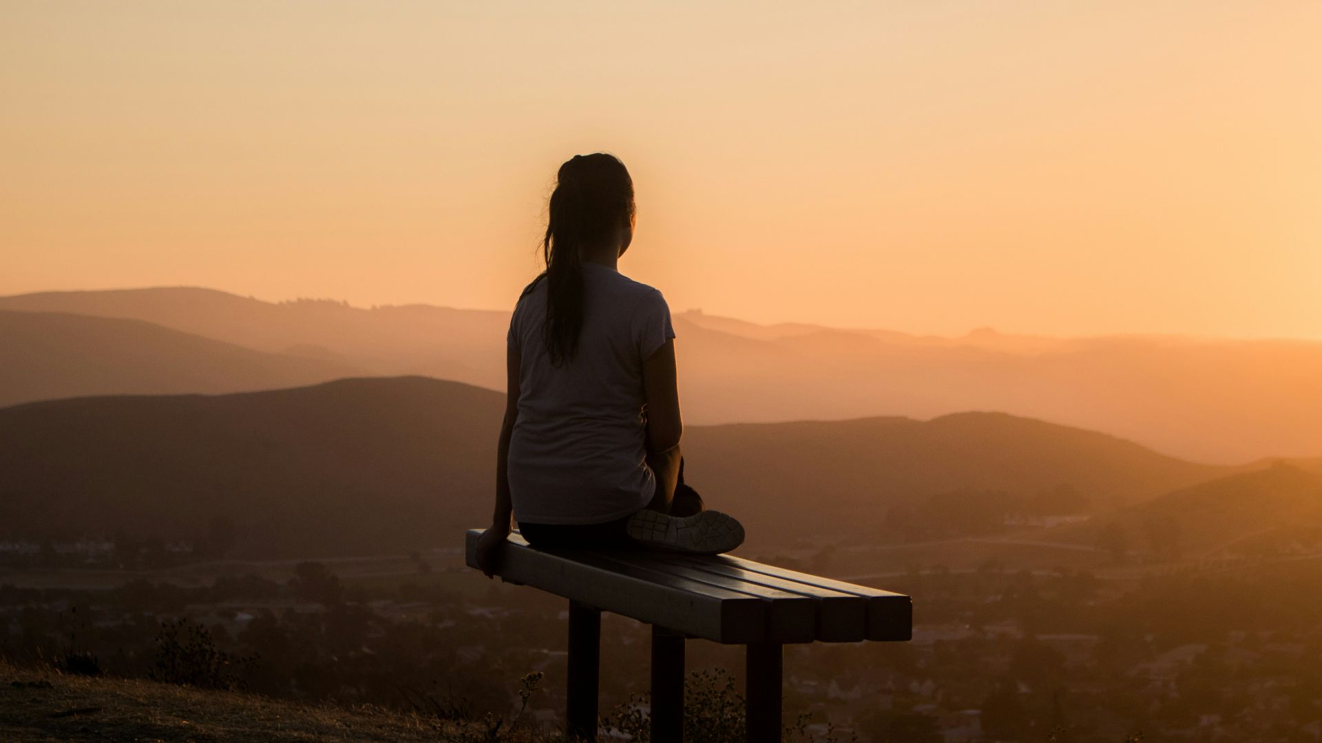 woman sitting on bench over viewing mountain