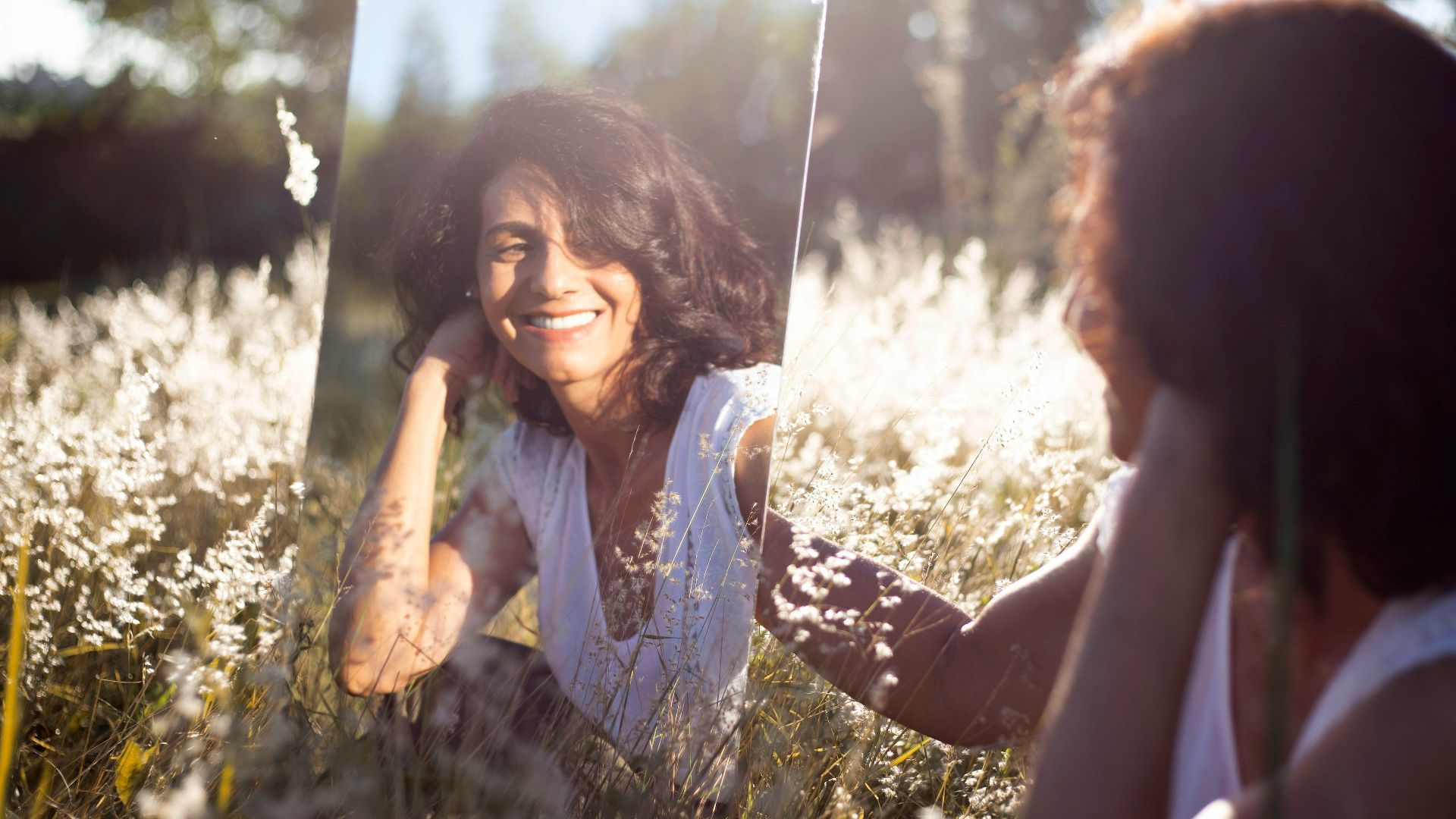 woman in blue and white floral shirt holding her face