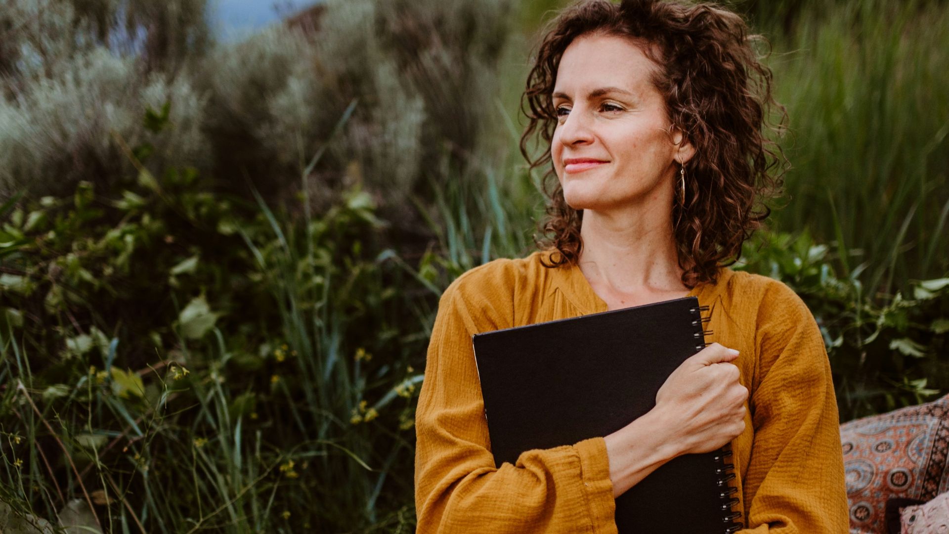 A woman in a yellow dress sitting on rocks