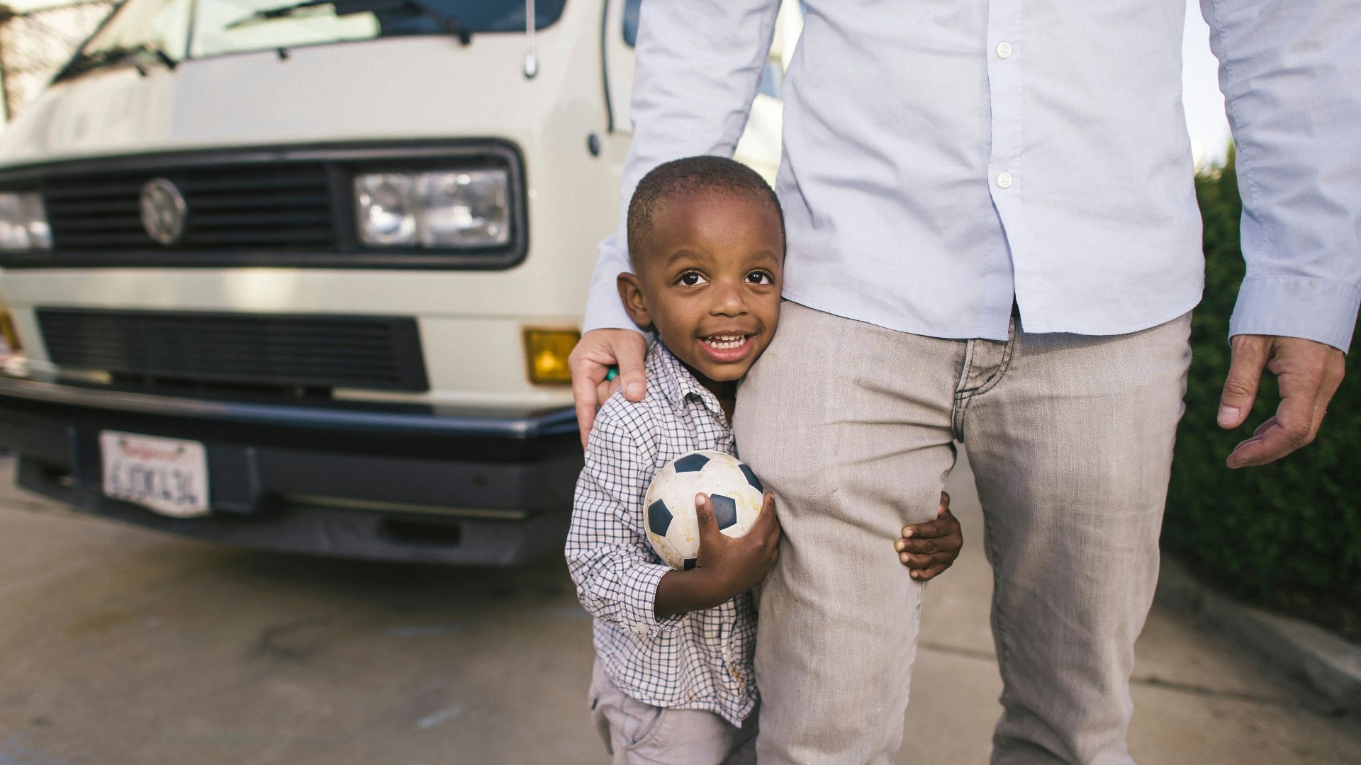 boy standing beside man in white dress shirr near vehicle