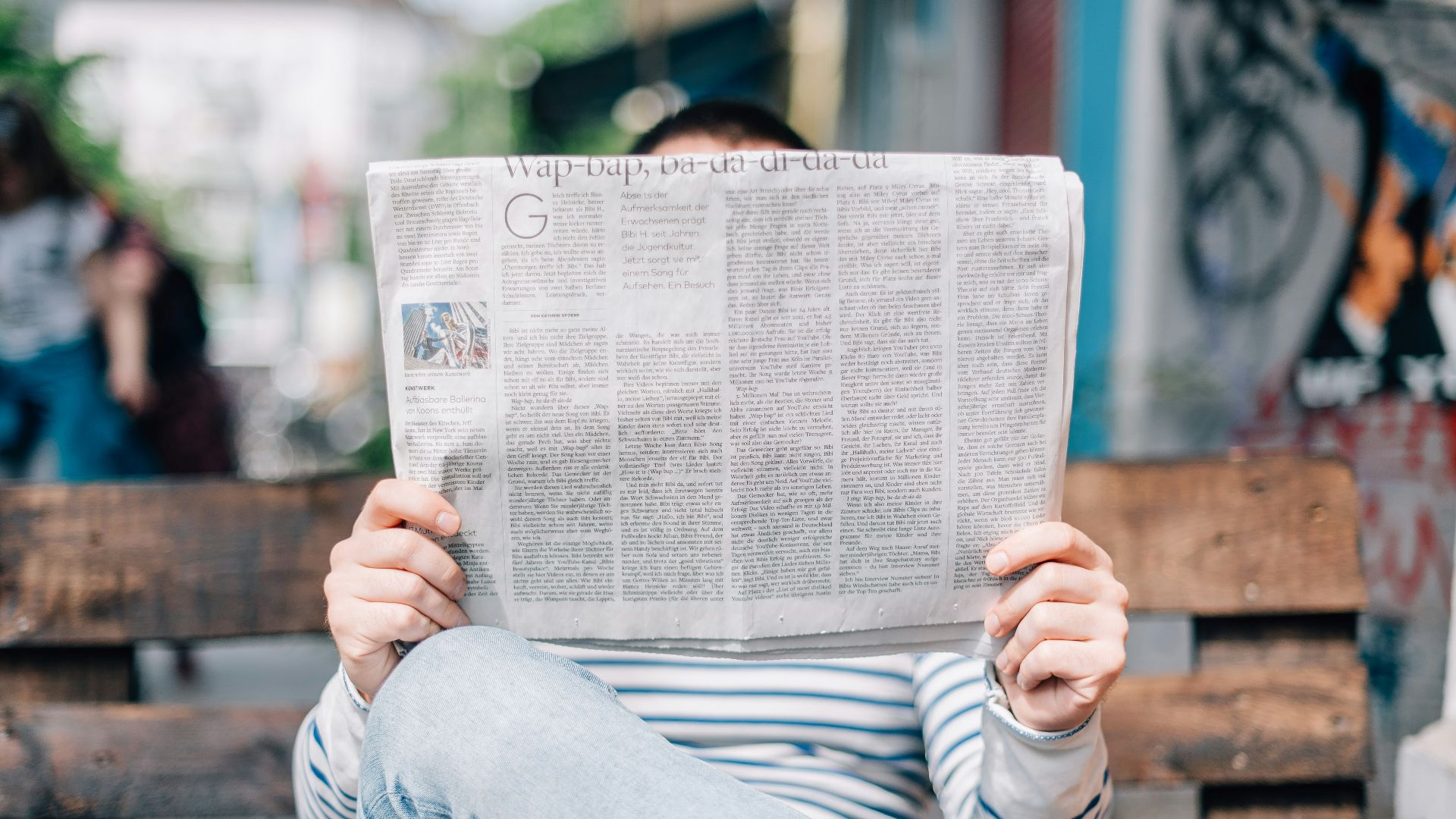 man sitting on bench reading newspaper