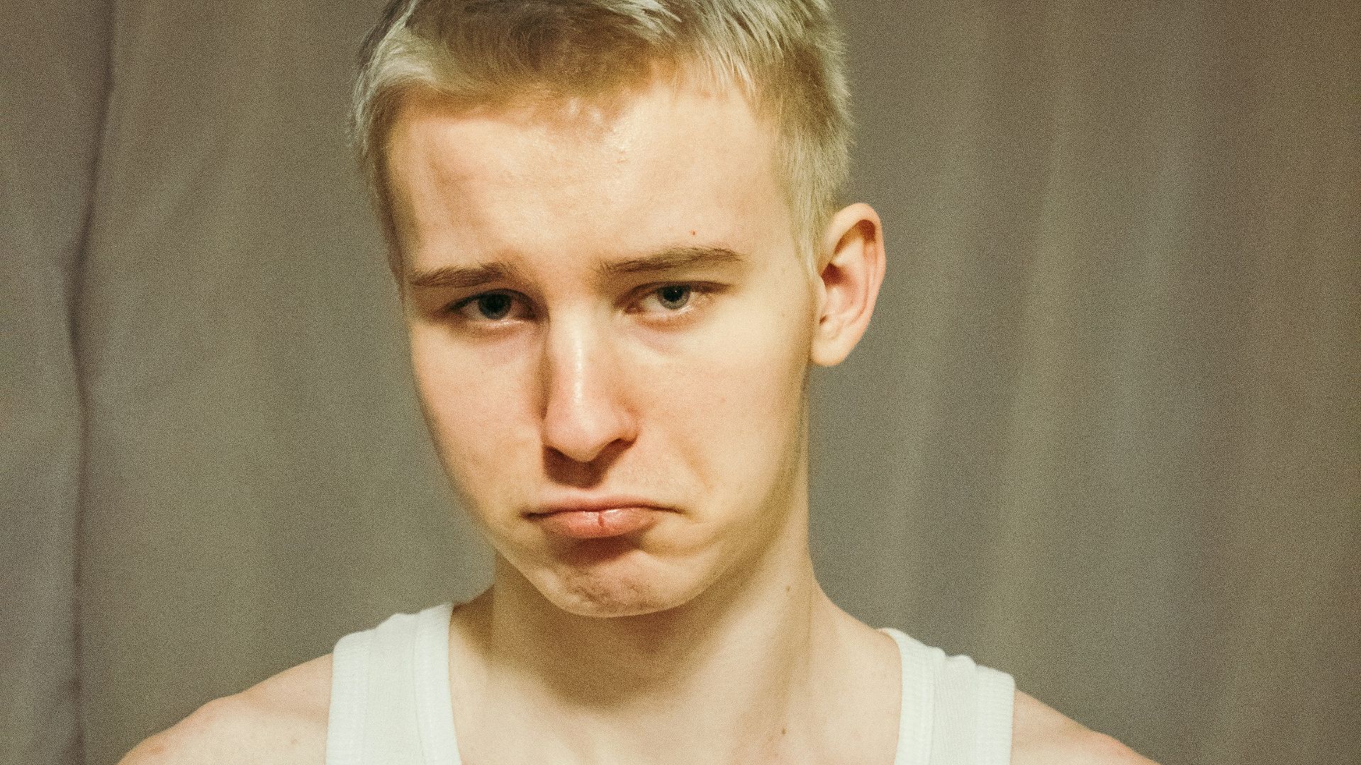 a man in a tank top is making a face