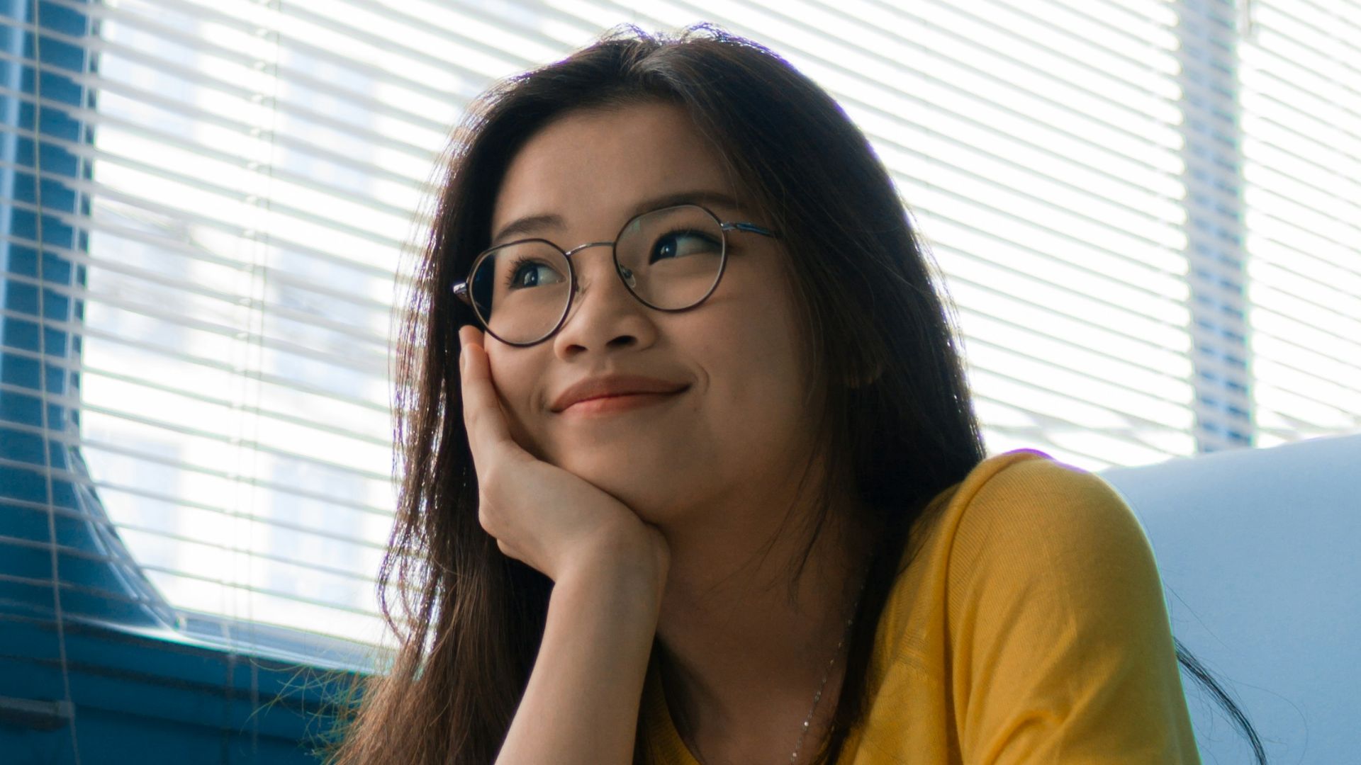 woman resting her chin on her palm while sitting on chair