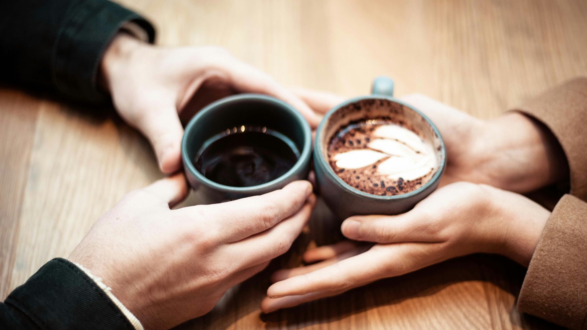 two person holding ceramic mugs with coffee