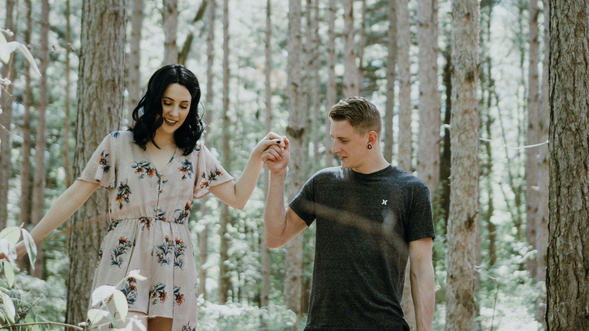 man holding hands with woman near trees
