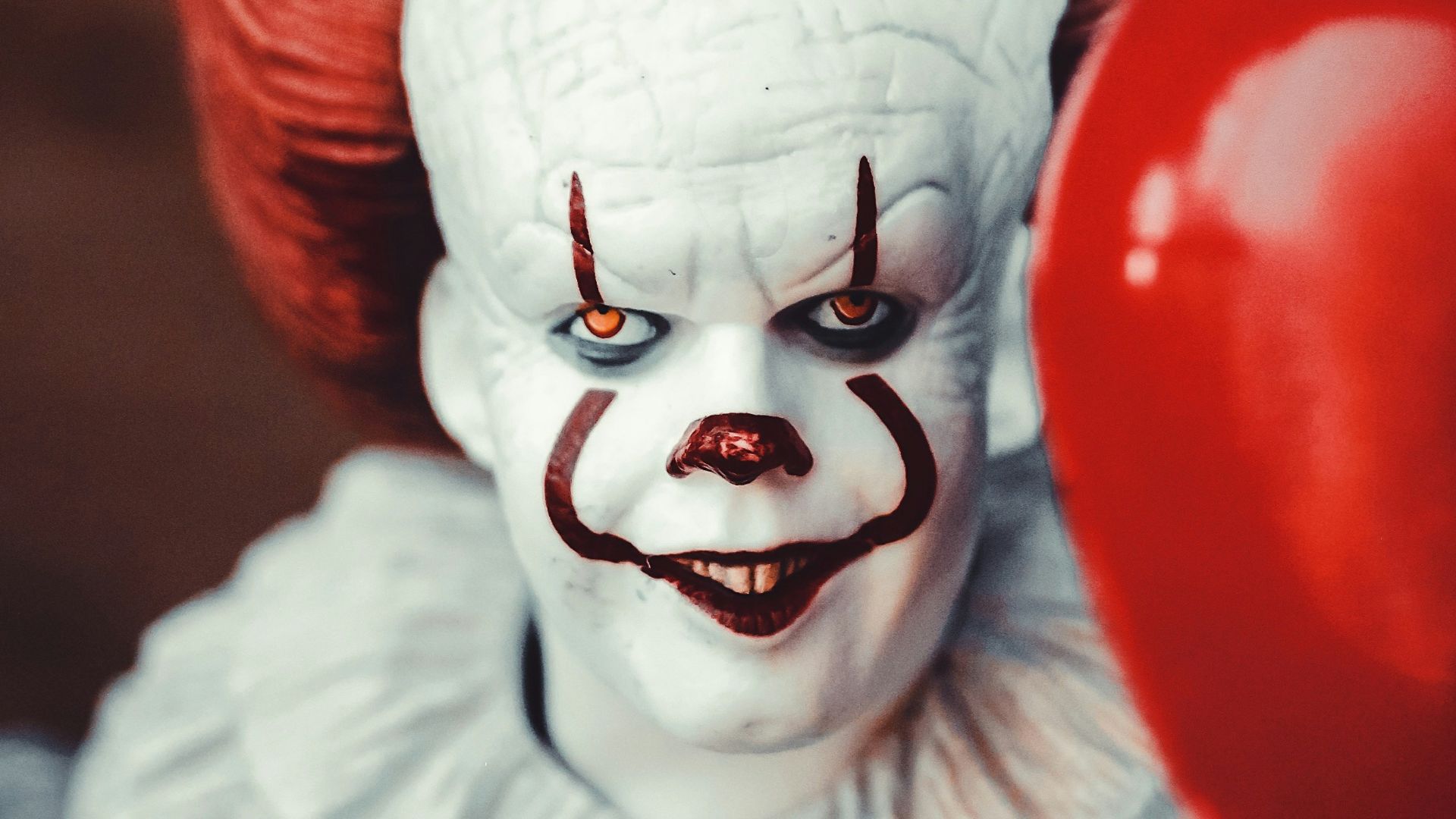 white and red clown holding heart balloon