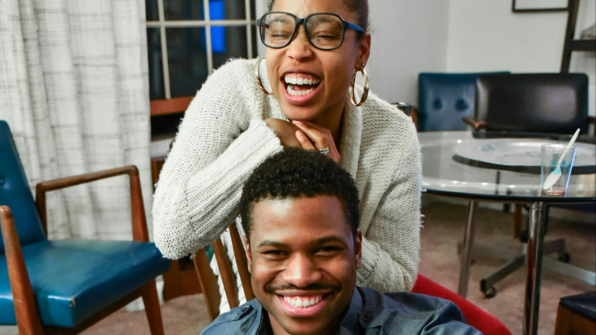 man sitting on floor beside woman smiling inside white painted room