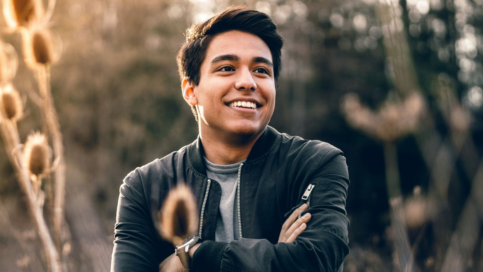 smiling man standing near green trees
