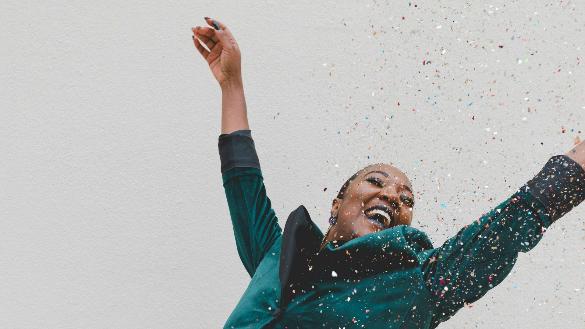 woman in green jacket raising her hands